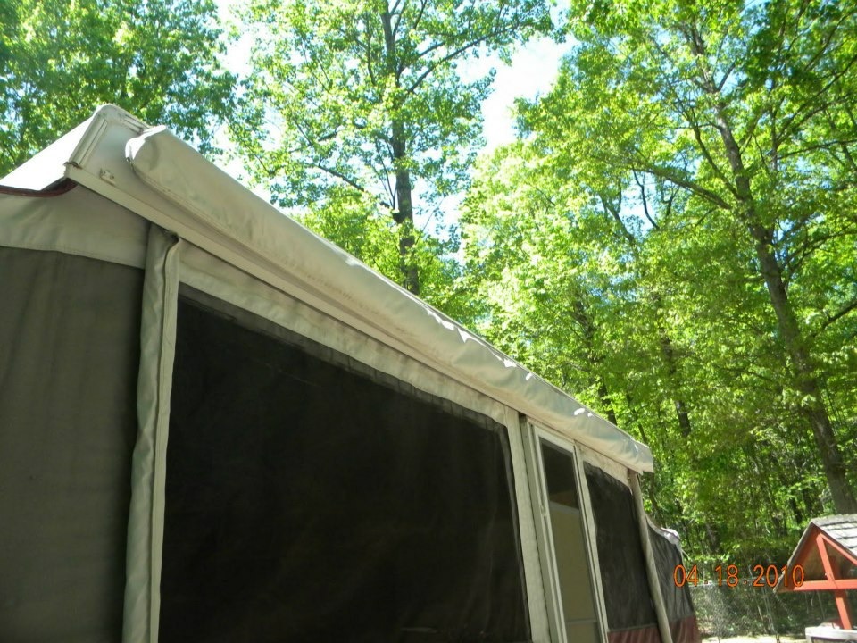 Binker Lee popup camper with the awning extended over a wooded campsite