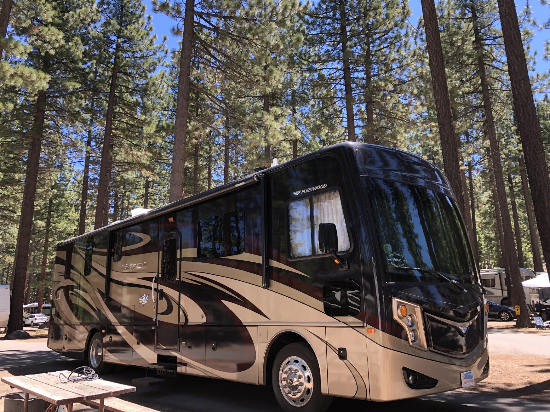 2016 Fleetwood Excursion 35E Class A motorhome parked among tall pine trees in a Lake Tahoe area campground
