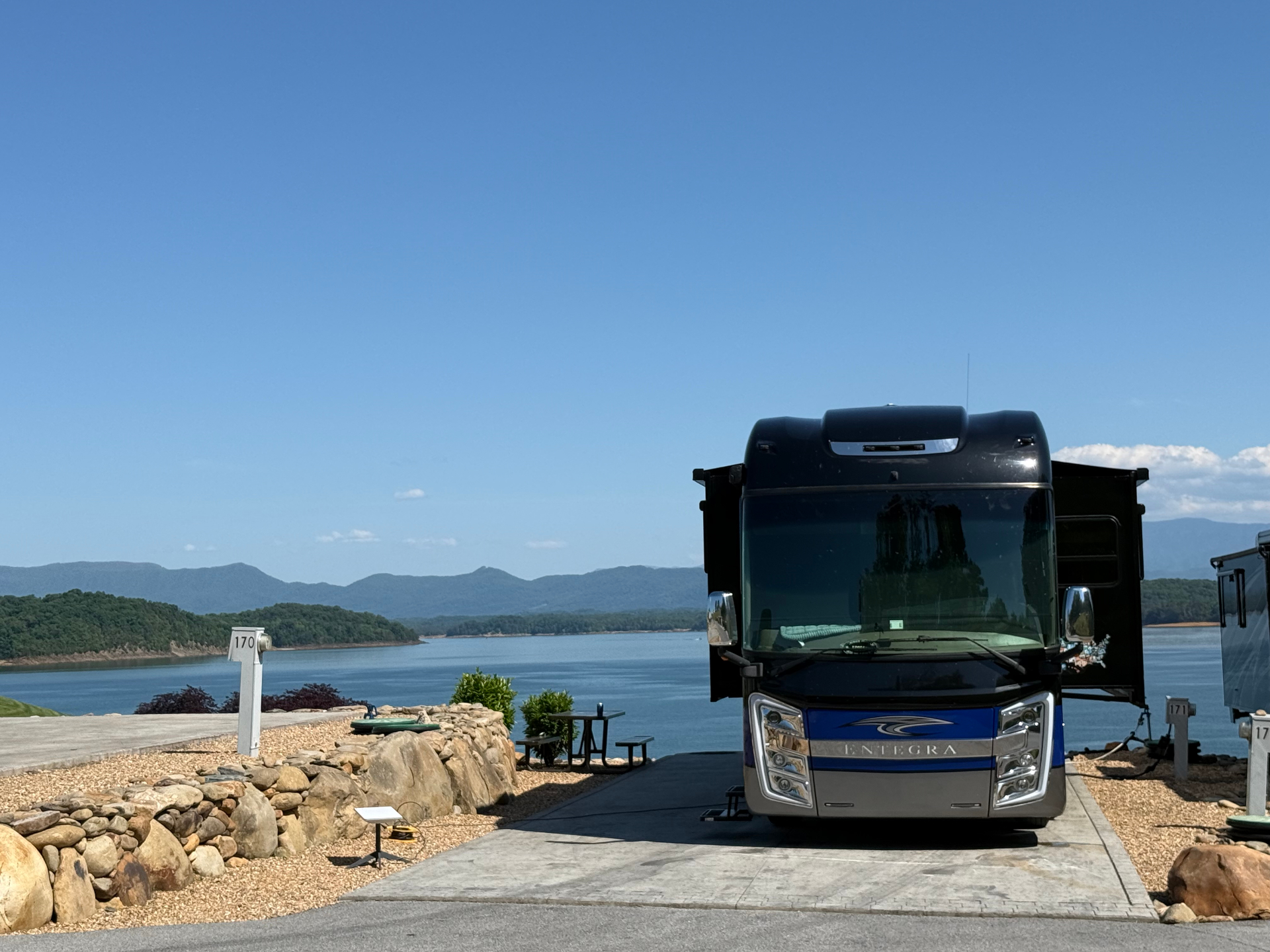 2021 Entegra Aspire 44W parked at a lakeside campsite with mountain views in the distance
