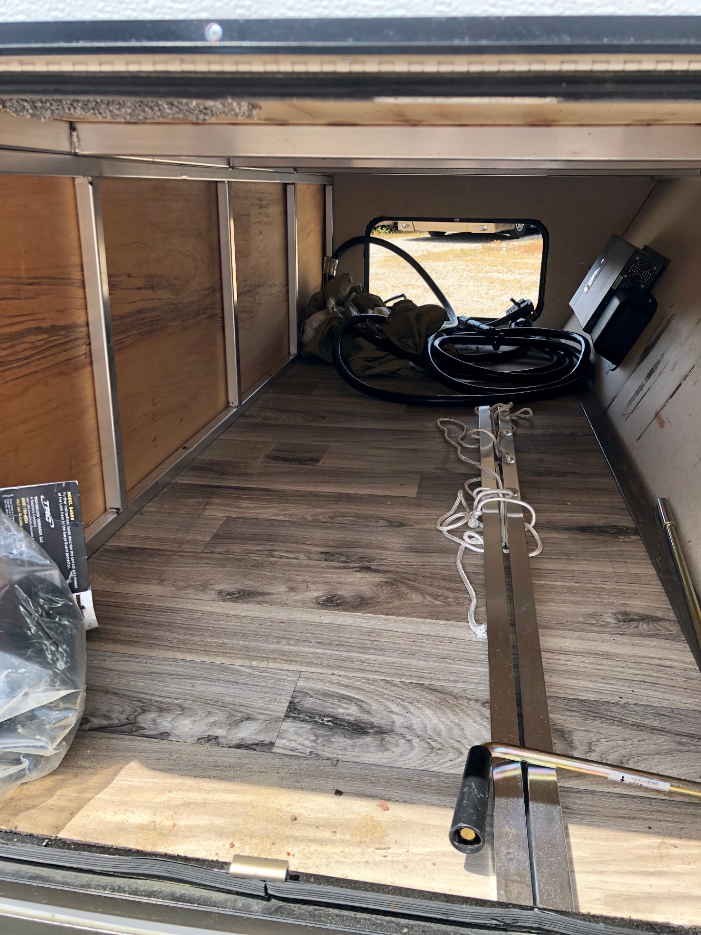 Open pass-through cargo storage on the 2018 Heritage Glen LTZ 312QBUD with utility gear on wood-look flooring