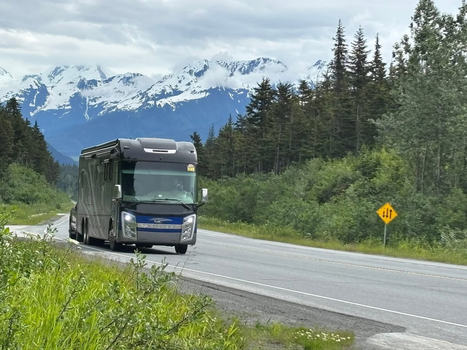 The Bordeaux RV on an Alaskan highway with snowcapped mountains