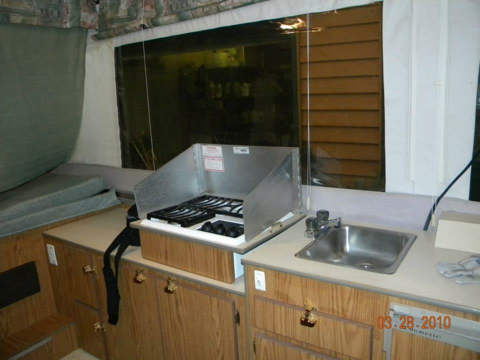 Interior galley of the Binker Lee with two-burner stove, sink, and overhead cabinets