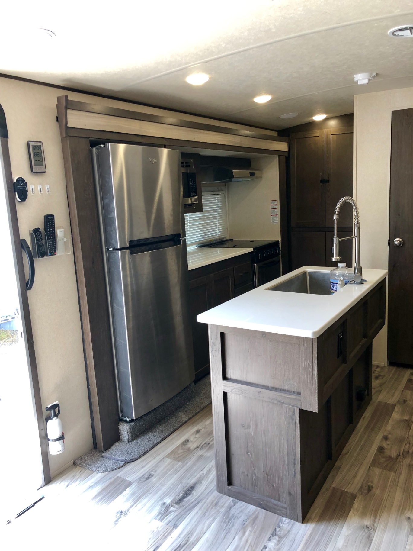 Kitchen entry view inside the 2018 Heritage Glen LTZ 312QBUD showing island sink, refrigerator, and stove