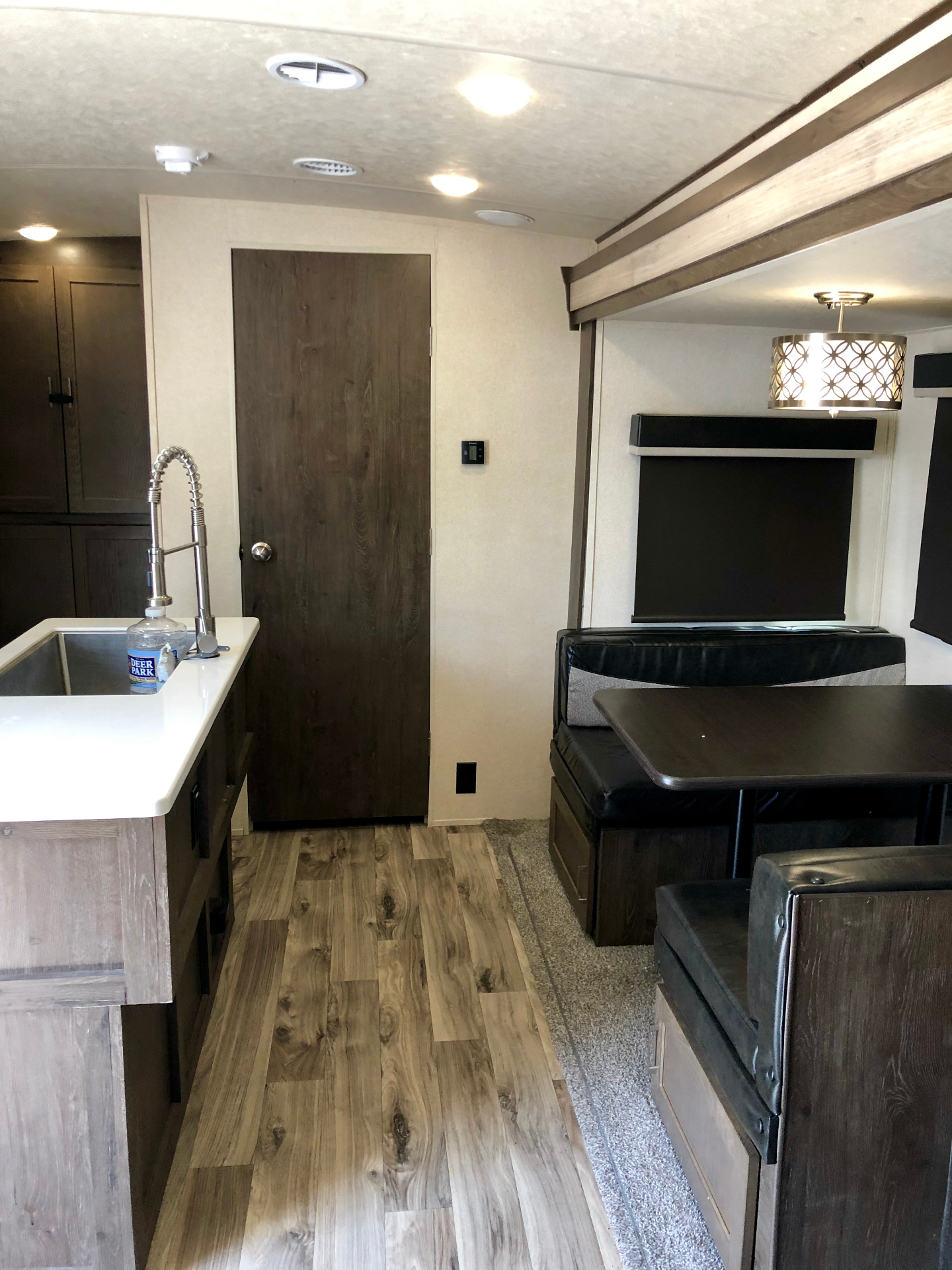 Interior view from the kitchen toward the living area dinette and TV inside the Heritage Glen LTZ 312QBUD