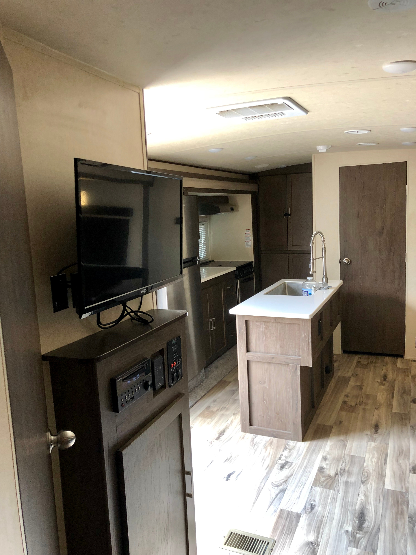 Living area and kitchen overview in the 2018 Heritage Glen LTZ 312QBUD with TV console and center island