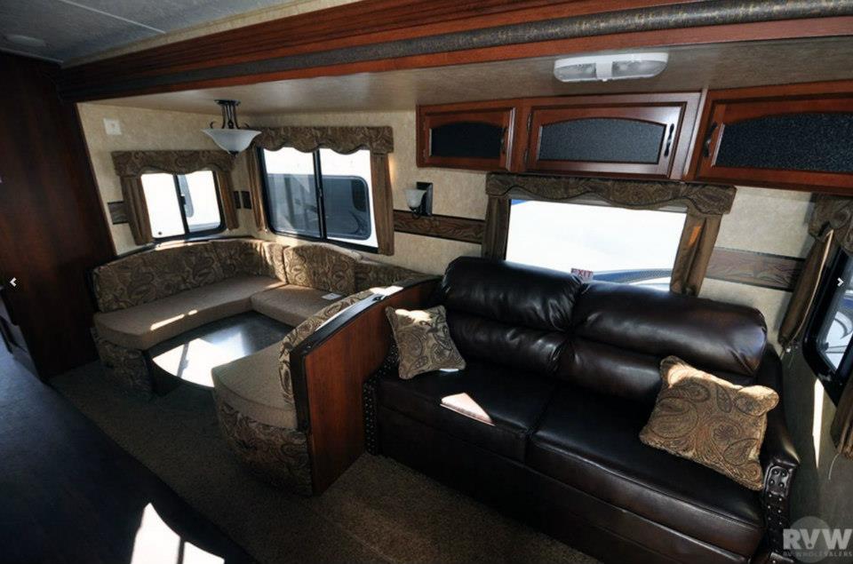 Heritage Glen 312QBUD living room with brown leather sleeper sofa and U-shaped dinette in the slide-out