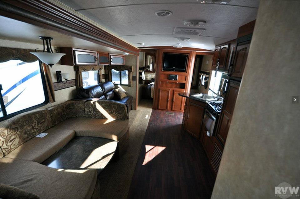 Wide interior view of the Heritage Glen 312QBUD from the front living room sectional toward the kitchen and master bedroom
