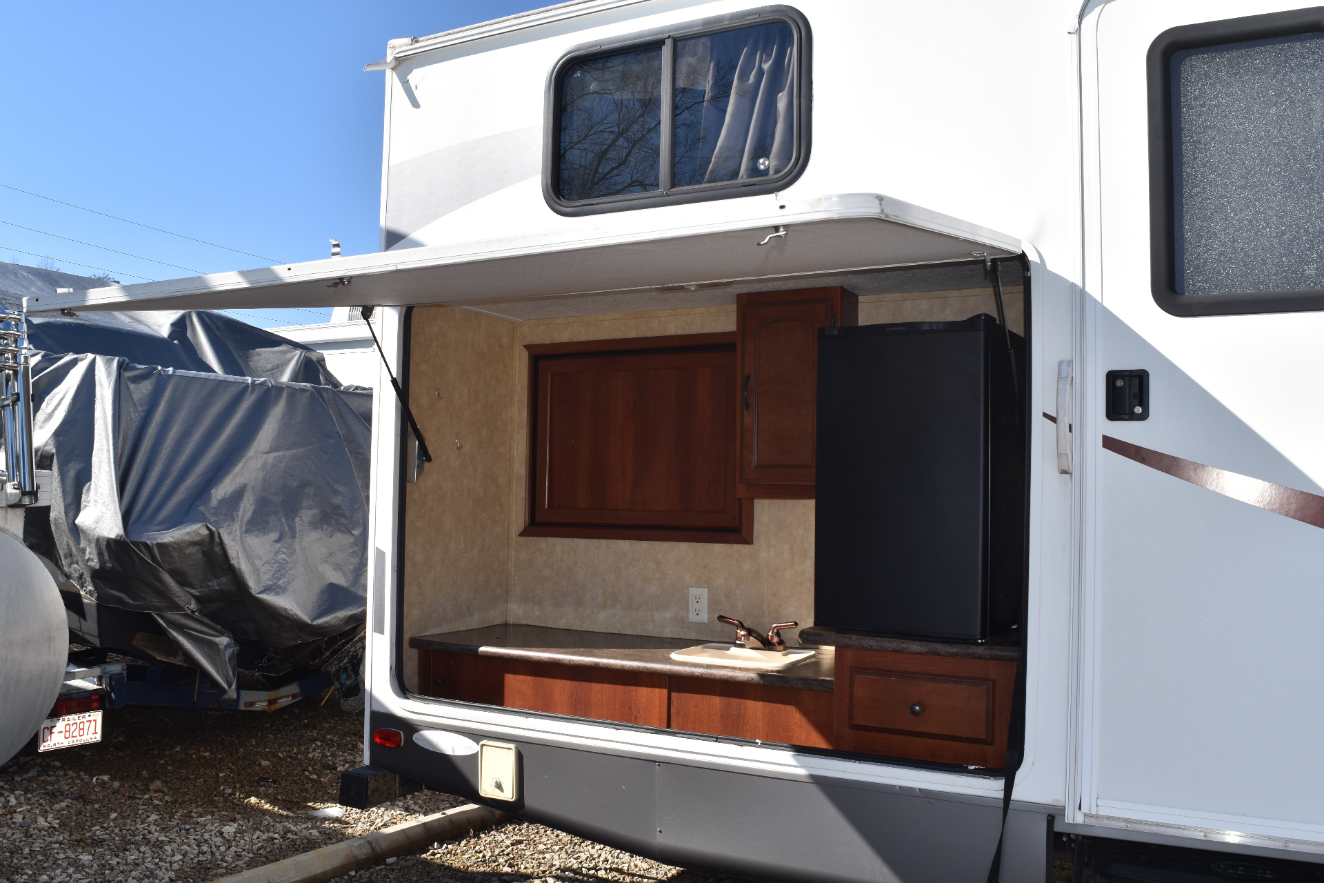 Wide exterior view of the Heritage Glen 312QBUD outdoor kitchen with the flip-up hatch open and awning extended
