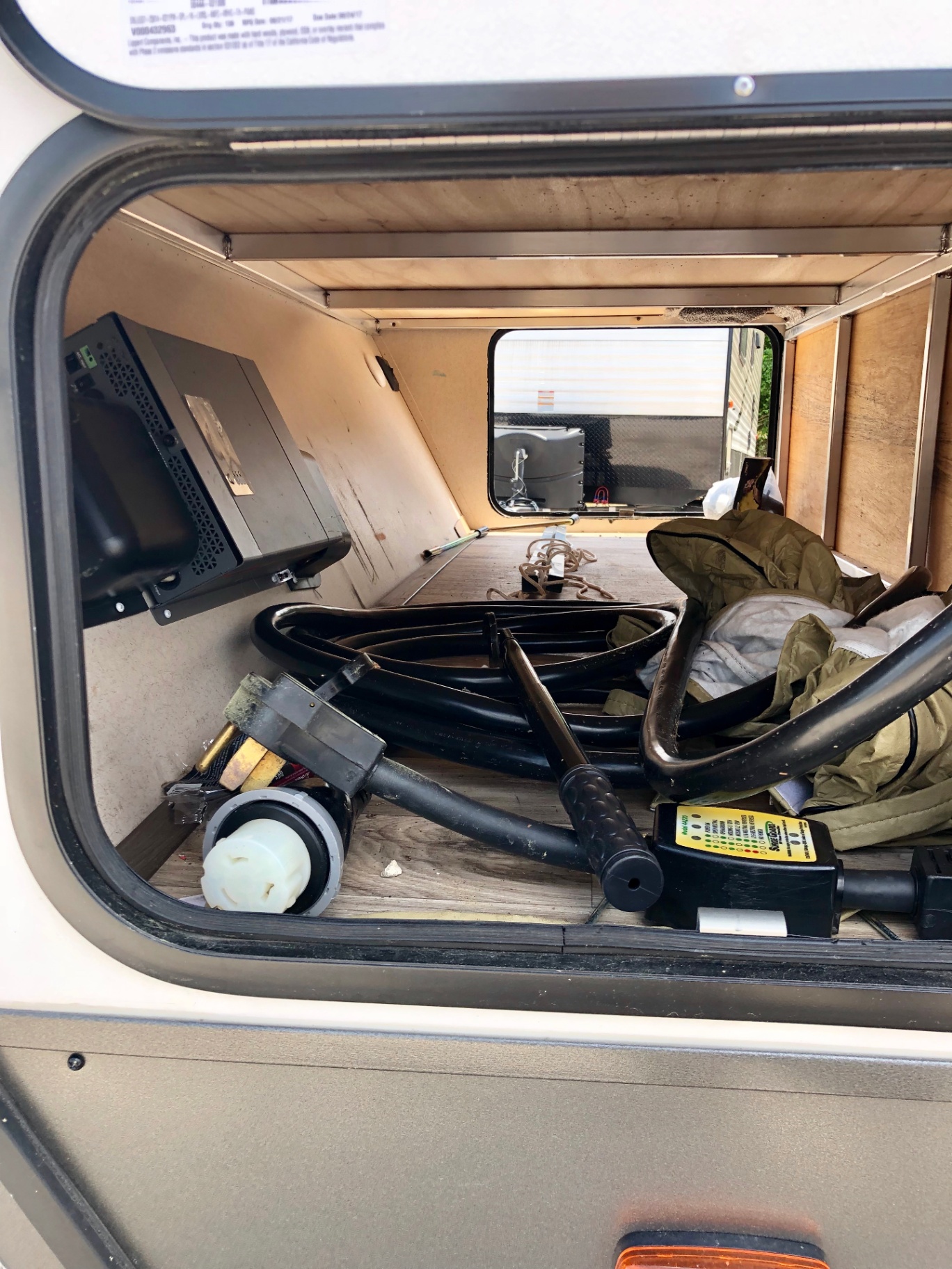 Front pass-through storage bay in the 2018 Heritage Glen LTZ 312QBUD with power cord, surge protector, and inverter
