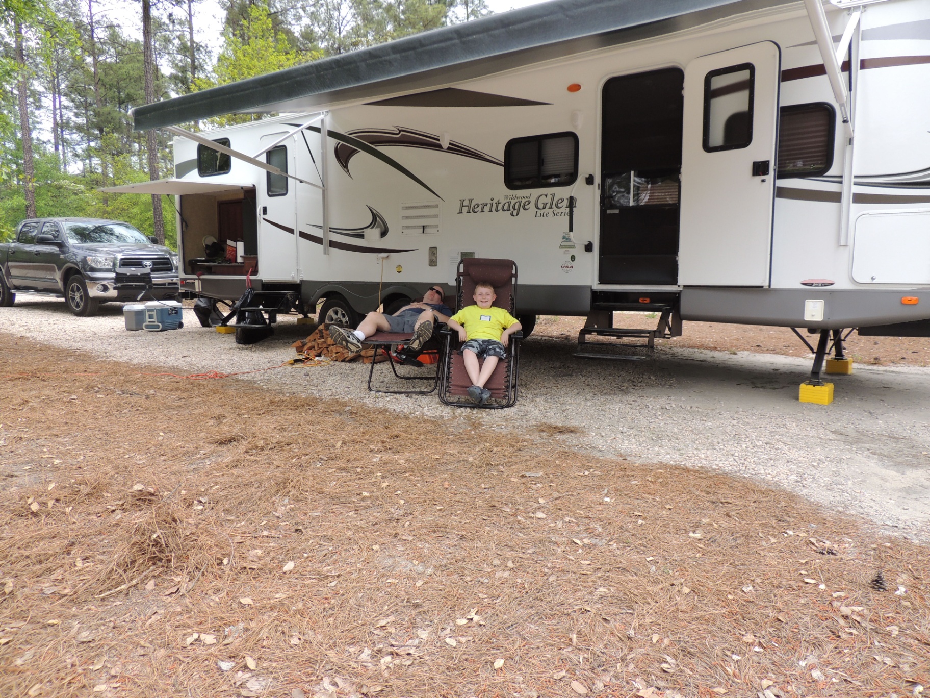 Father and son relaxing in zero-gravity chairs at the Heritage Glen 312QBUD campsite