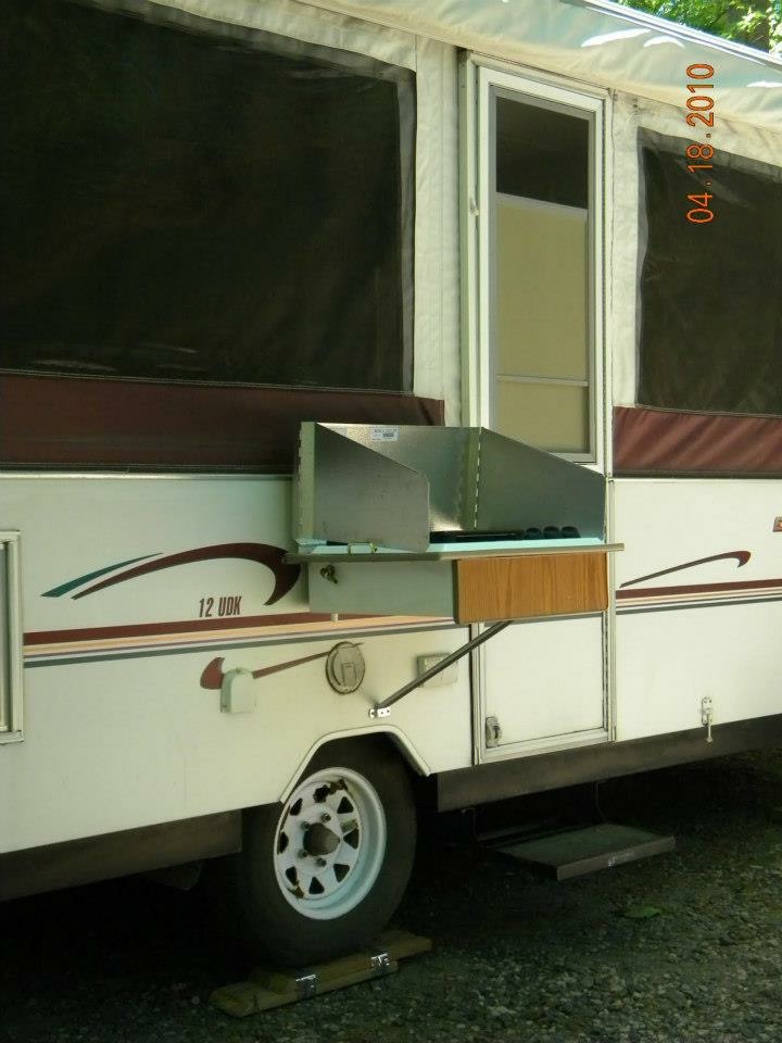 Side profile of the Binker Lee popup camper with the exterior stove deployed at the campsite