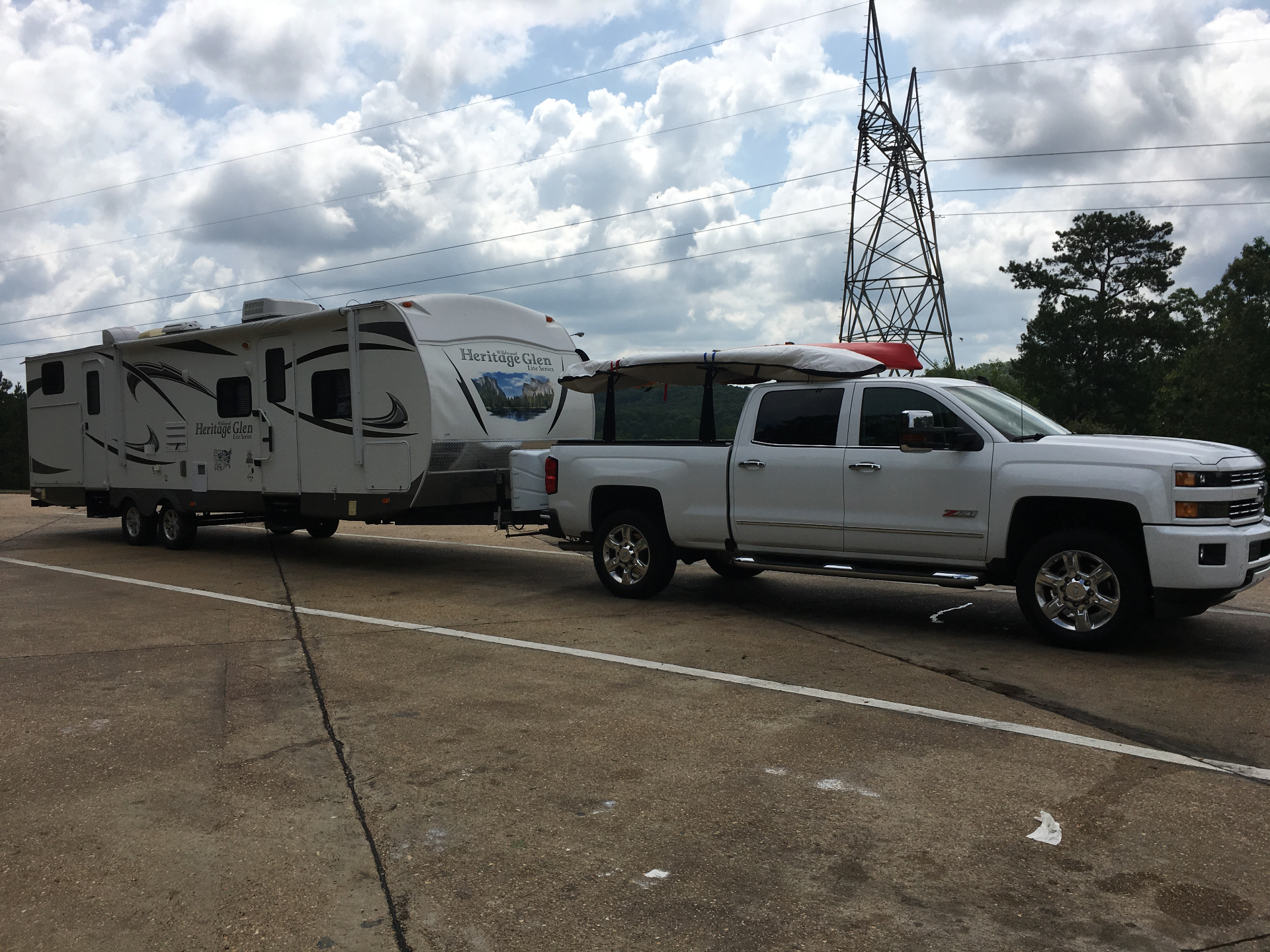 Heritage Glen 312QBUD being towed by a white Chevy Silverado Z71 with kayaks on the rack at a highway pull-off