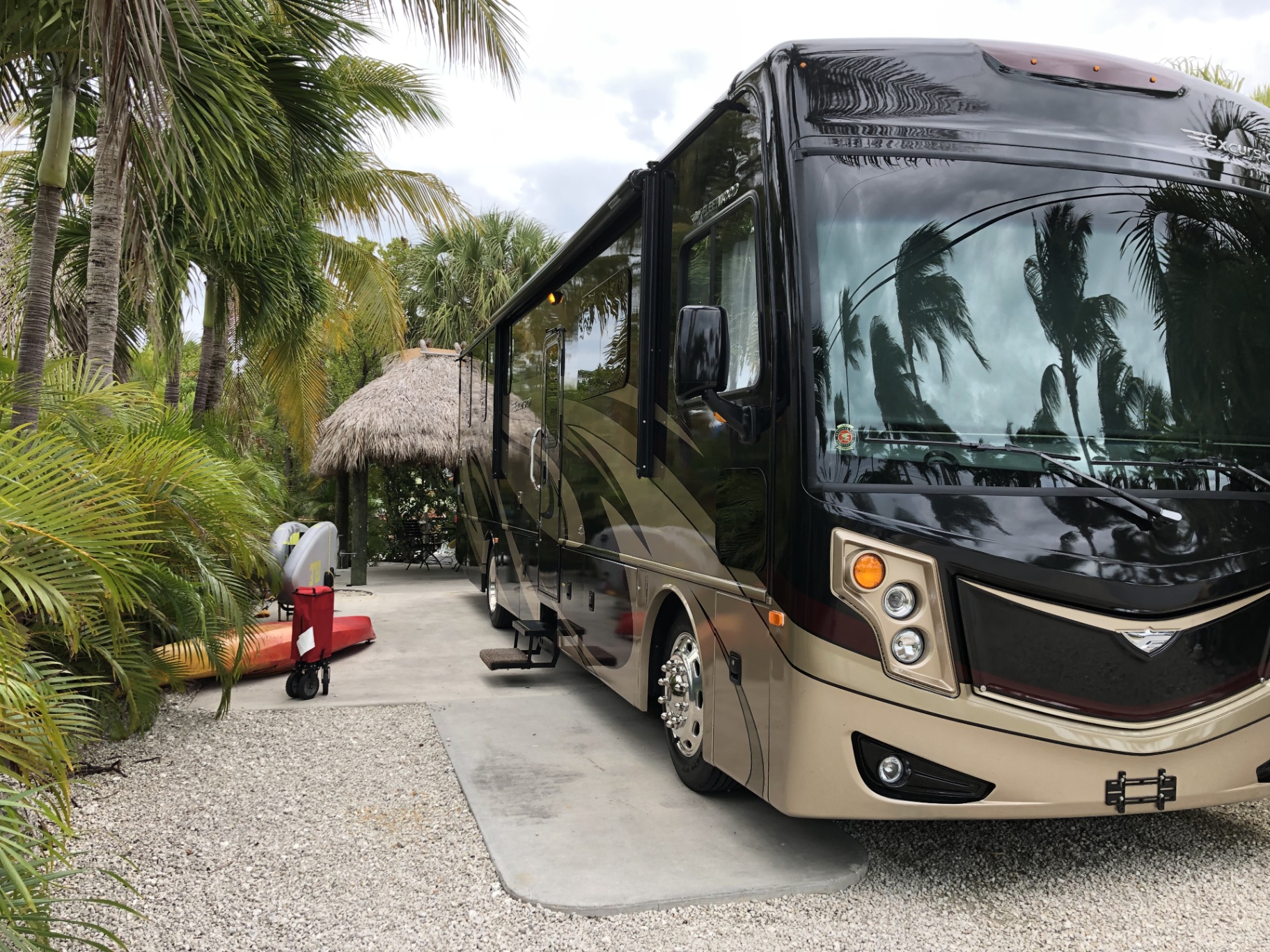 2016 Fleetwood Excursion 35E parked at a tropical Florida Keys campsite with palm trees and a thatched tiki hut