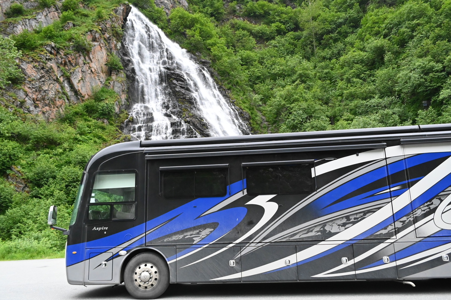 Wild Blue Yonder, a 2021 Entegra Aspire 44W motorhome, parked beside a waterfall in Alaska